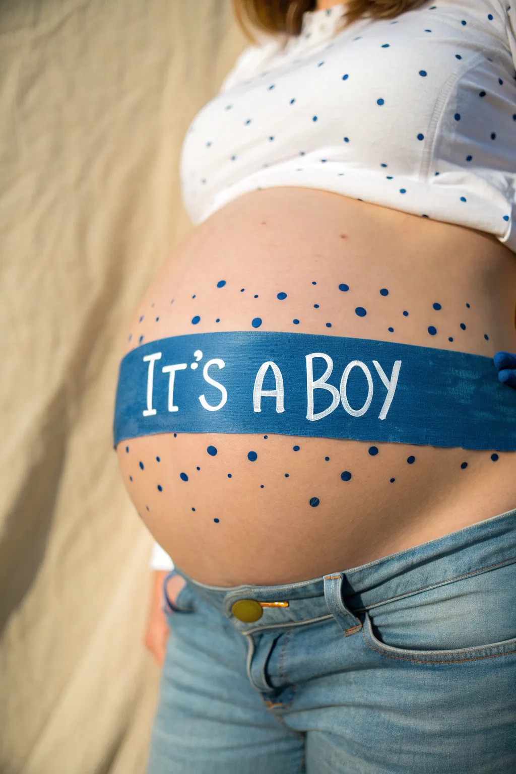 Scandi minimal belly painting in soft blues with ribbon banner and confetti for a sweet baby boy reveal.