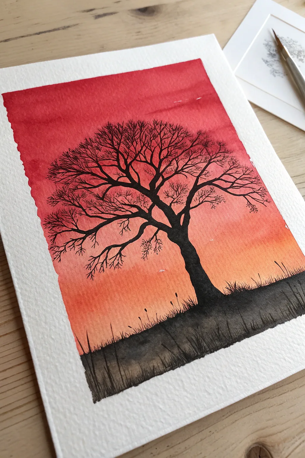 Striking black silhouette tree against a red gradient sky, minimalist and boldly contrasted.