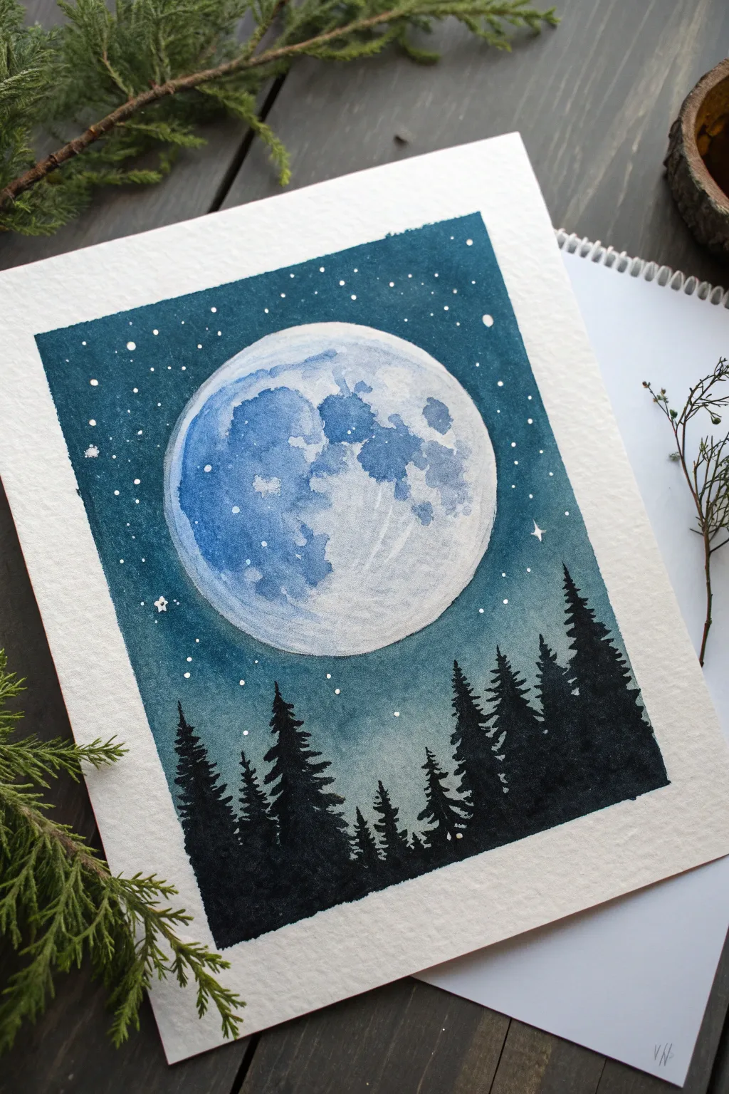 Midnight blue moonlit sky painting with crisp pine silhouettes and soft glowing moon contrast