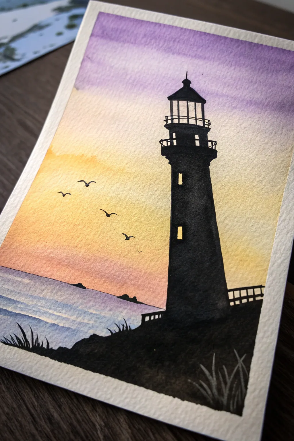 Paint a bold lighthouse silhouette over a dreamy sunset gradient for an easy coastal classic.