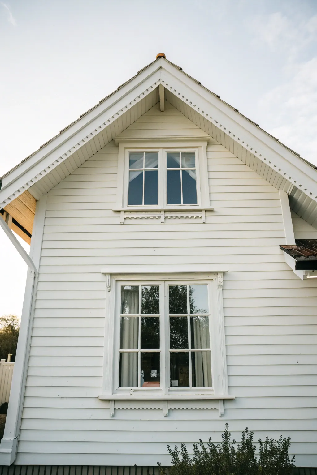 Classic white exterior with crisp trim that cleanly outlines windows and eaves in daylight