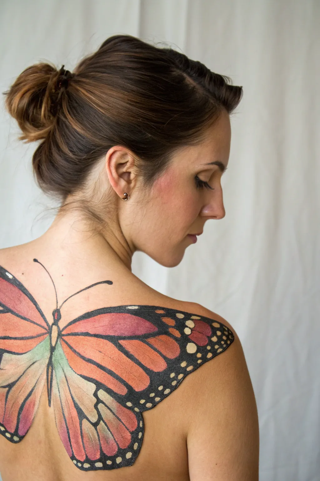 Soft butterfly wings painted across shoulder blades, crisp lines and airy gradients in calm studio light.