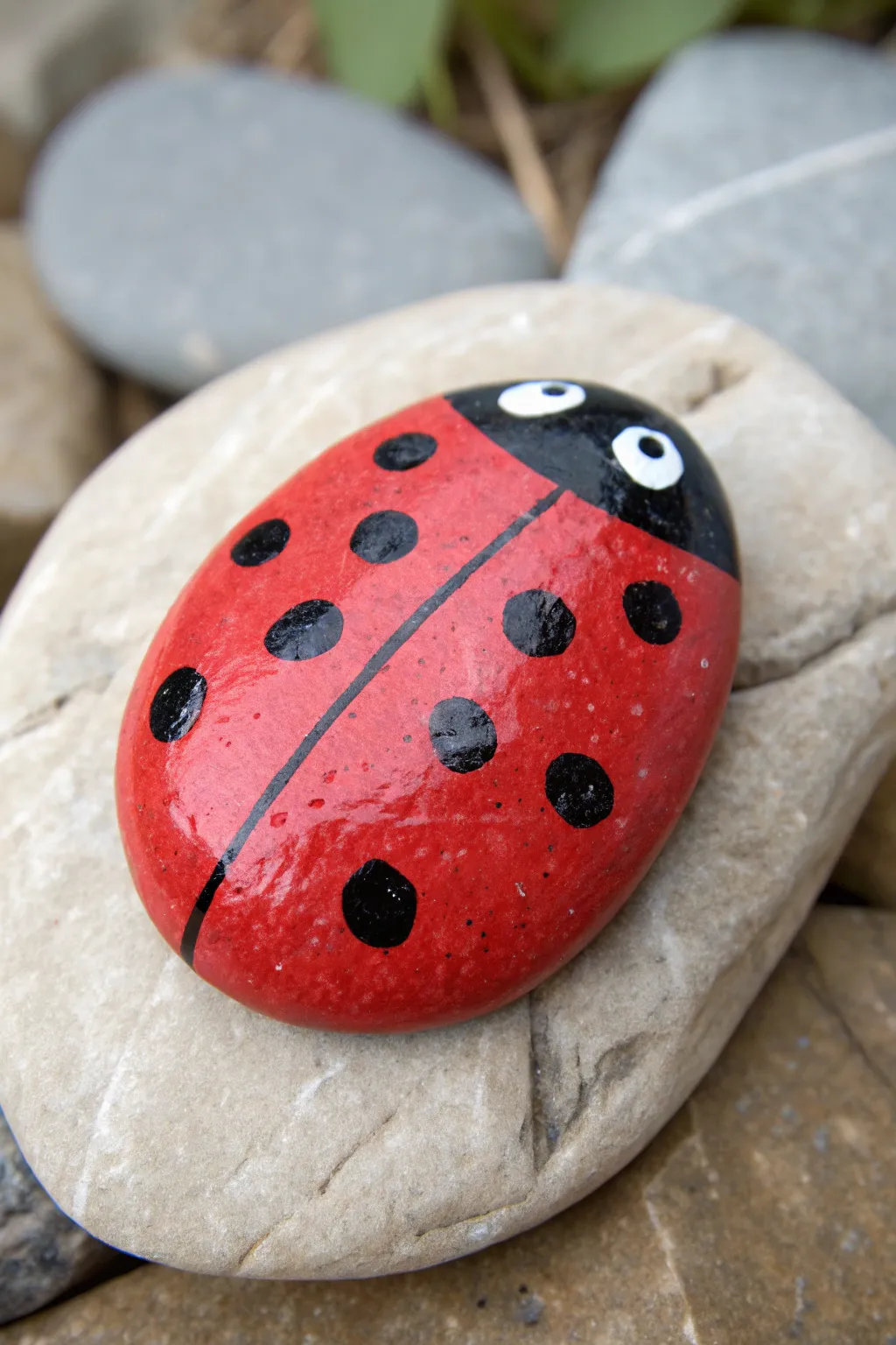 Paint a classic red ladybug on an oval rock for a charming, minimalist garden vibe.