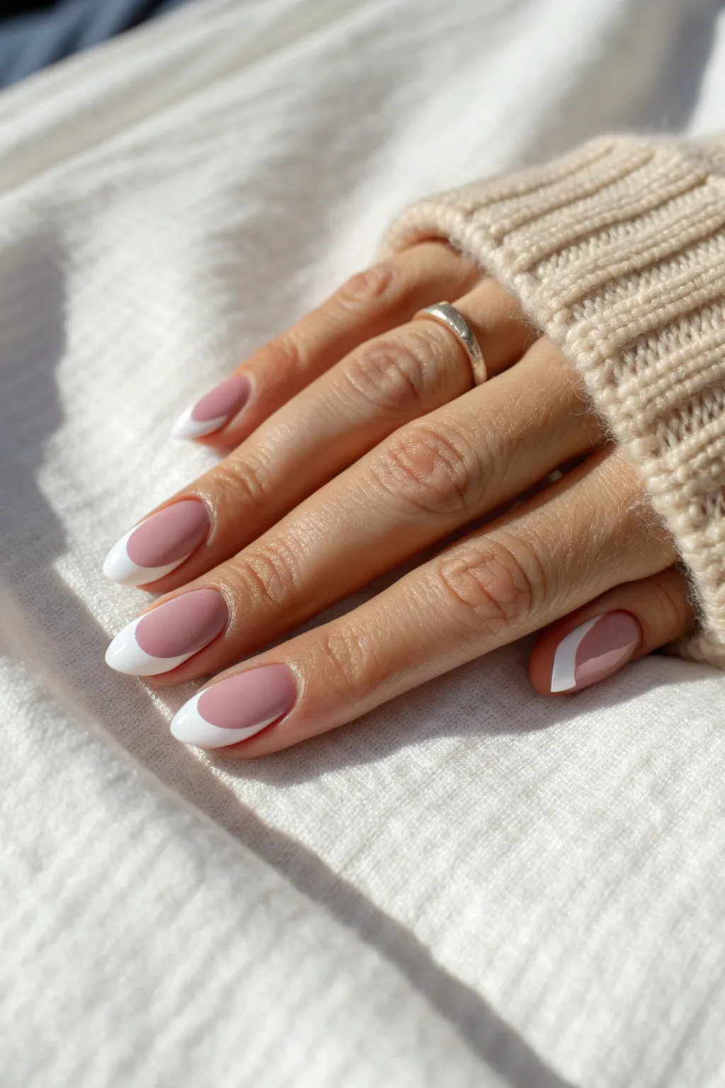 Classic French tip nails: crisp white edges on a sheer pink base in soft daylight minimalism