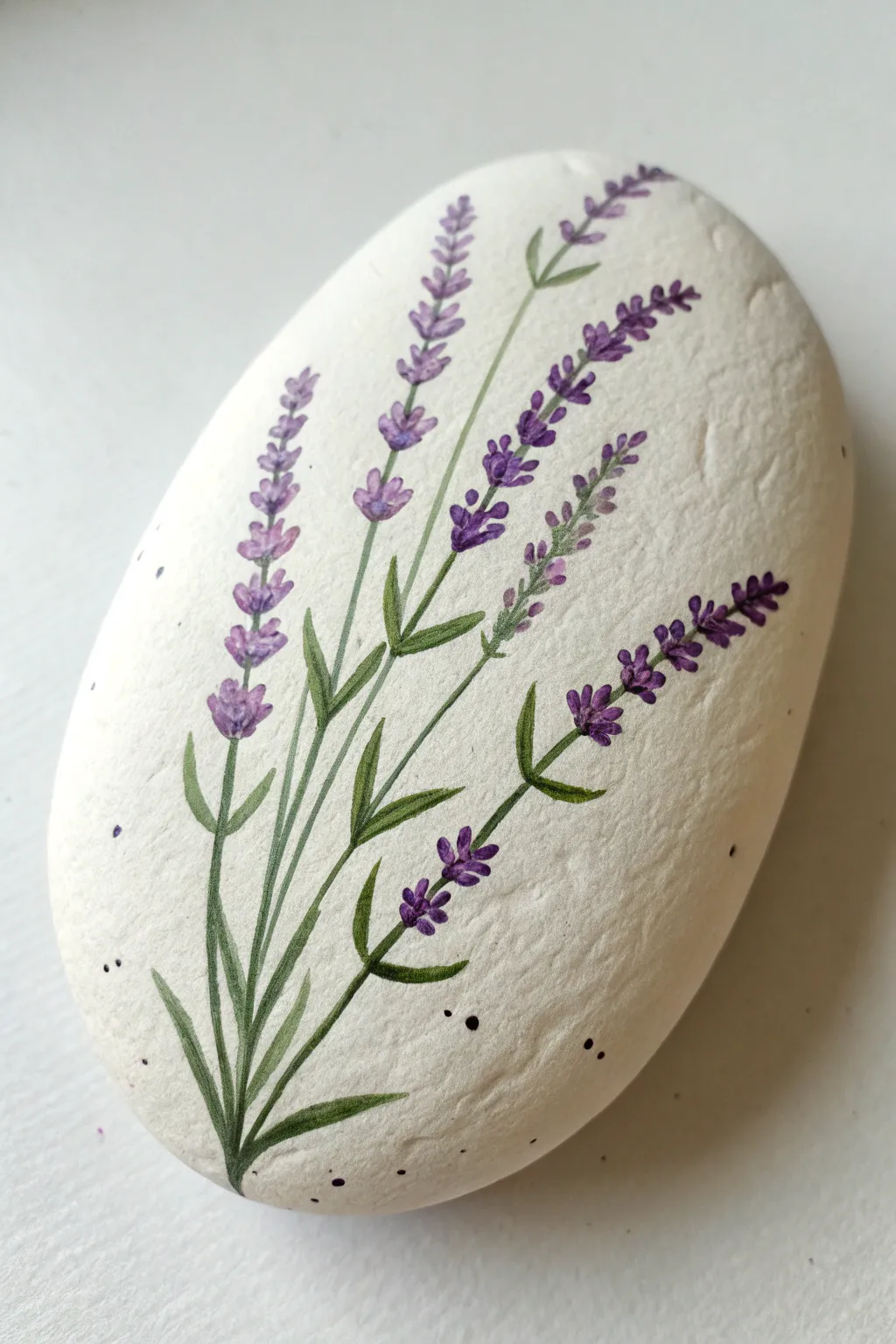 White-washed rock with delicate lavender sprigs for serene purple rock painting inspiration.