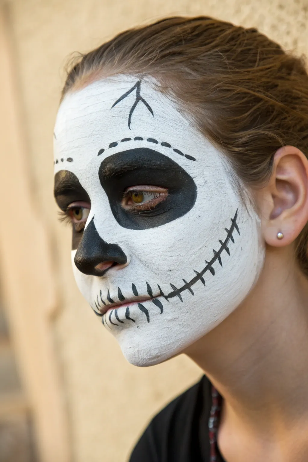 Easy classic skull face paint: crisp white base, hollow eyes, simple teeth lines, clear front view.