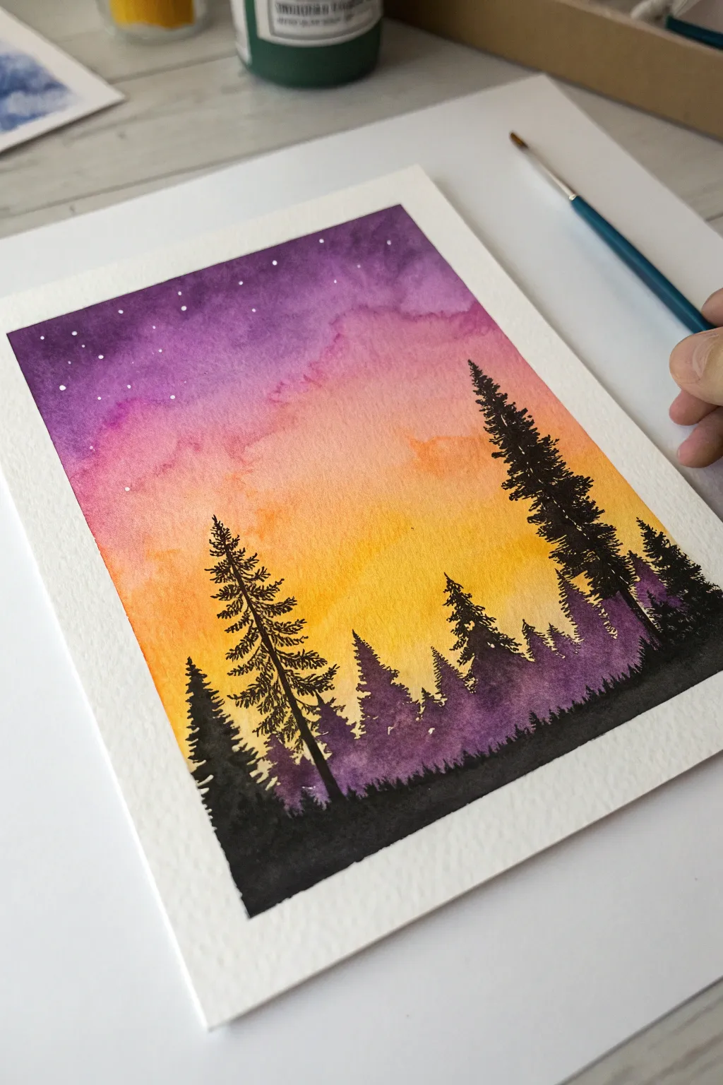 Classic sunset tree line silhouette: bold black forest against a warm gradient sky