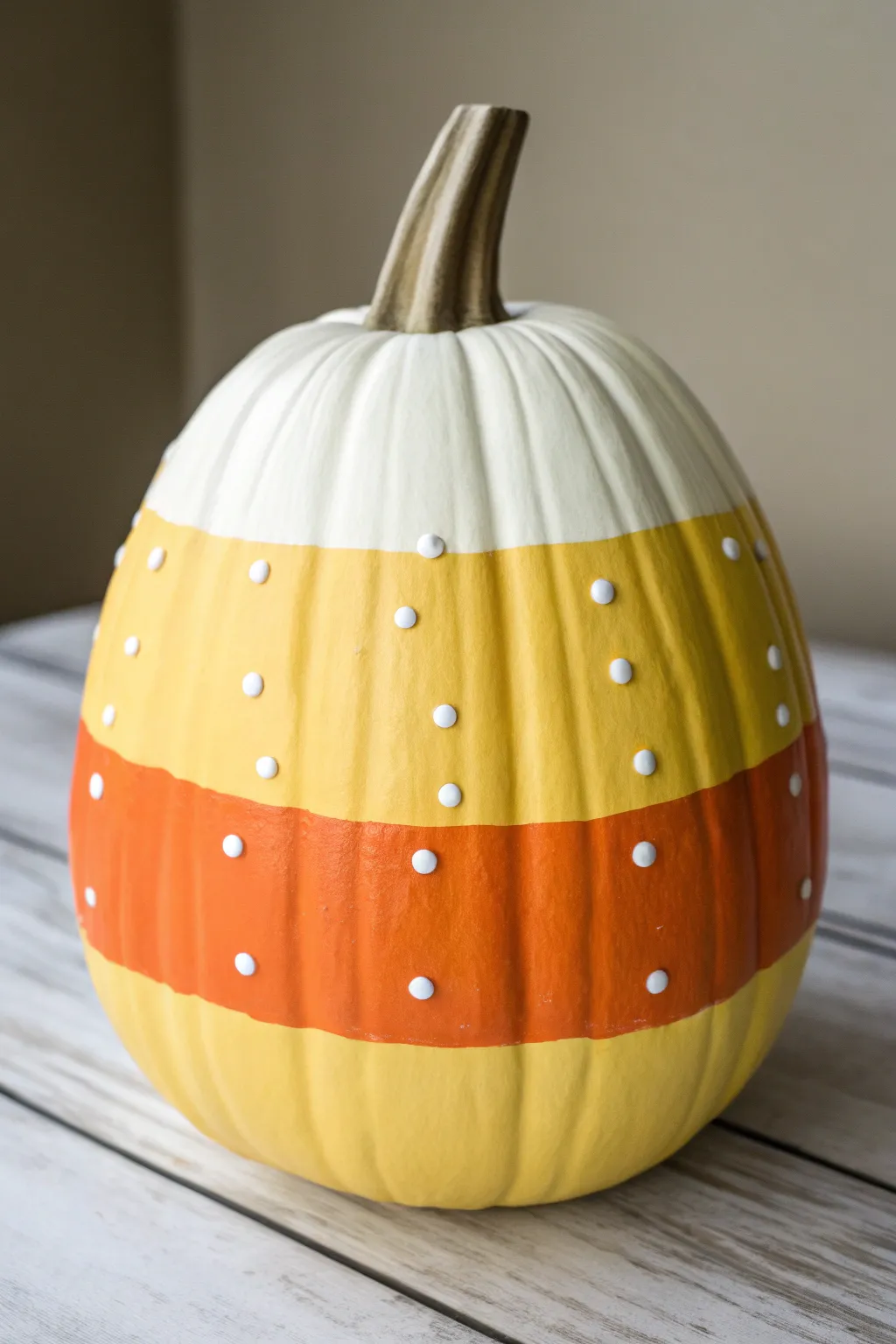 Striped candy corn pumpkin with playful white dots, minimal boho styling and cozy contrast.