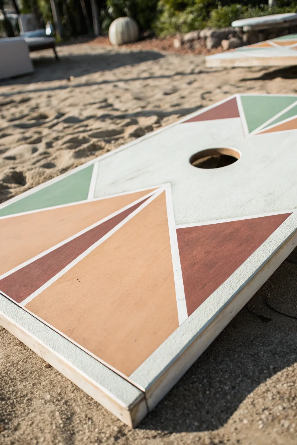 Offset geometric blocks in earthy tones for a modern cornhole board paint idea with matching bags