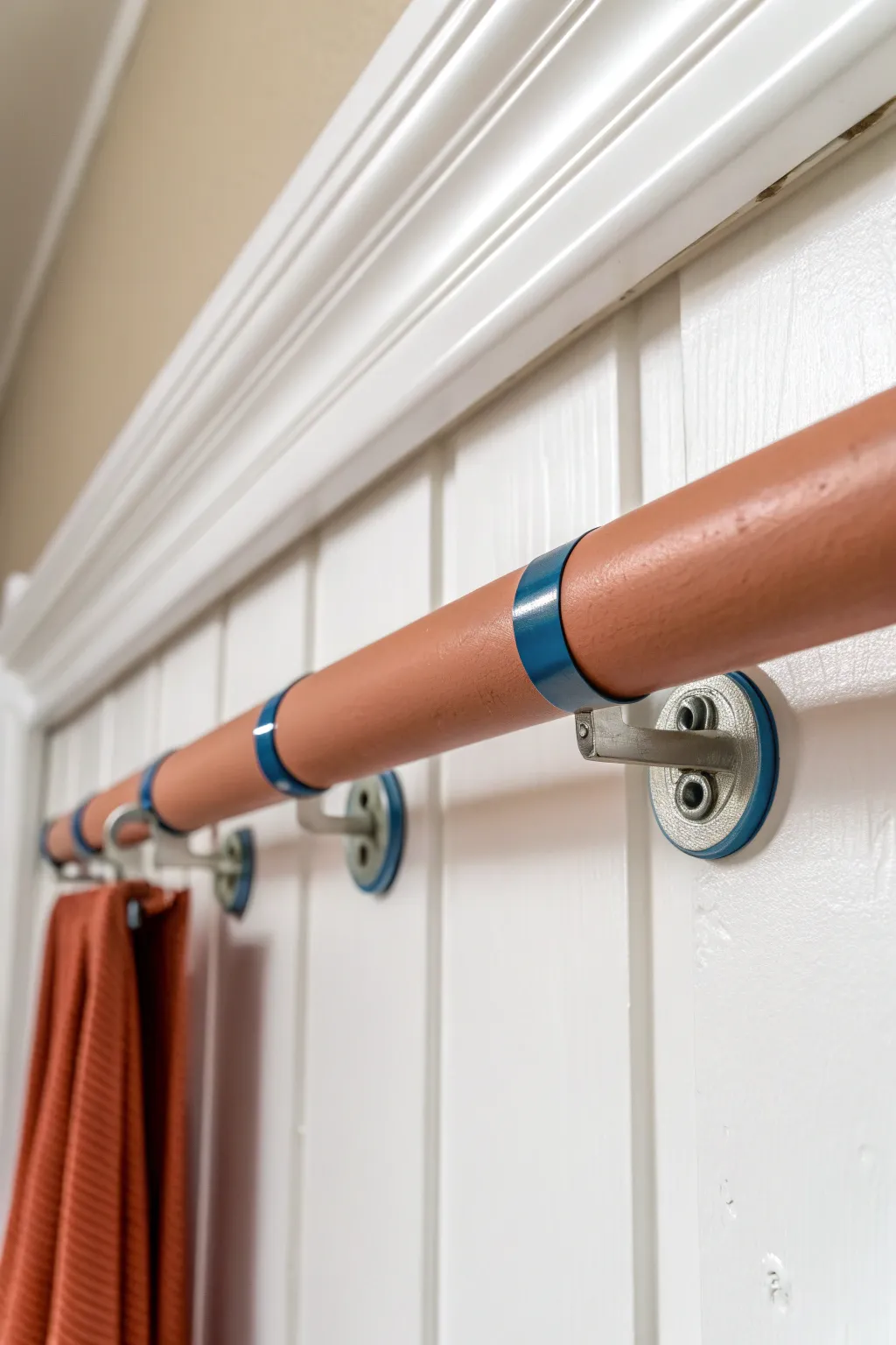 Mini hardware makeover: matte terracotta closet rod with matching brackets and a taped off before section.