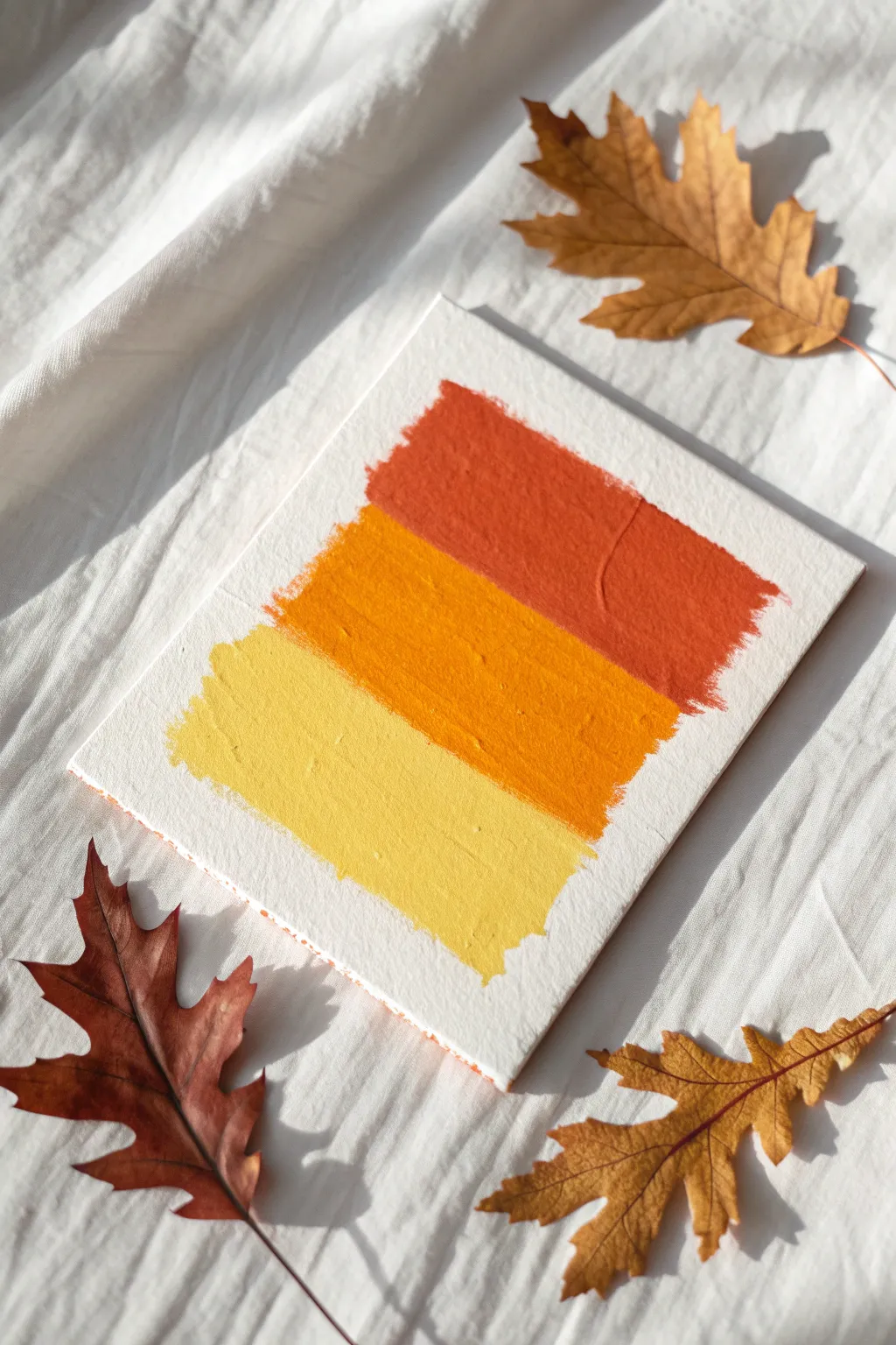 Minimal candy corn color-block painting with tiny fall leaves for an easy modern autumn look