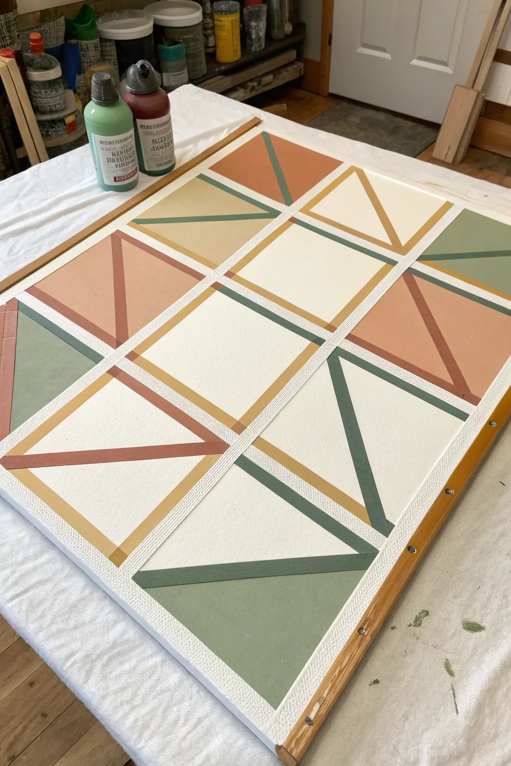 Mid-process tape-line web on canvas with soft boho colors for easy geometric painting