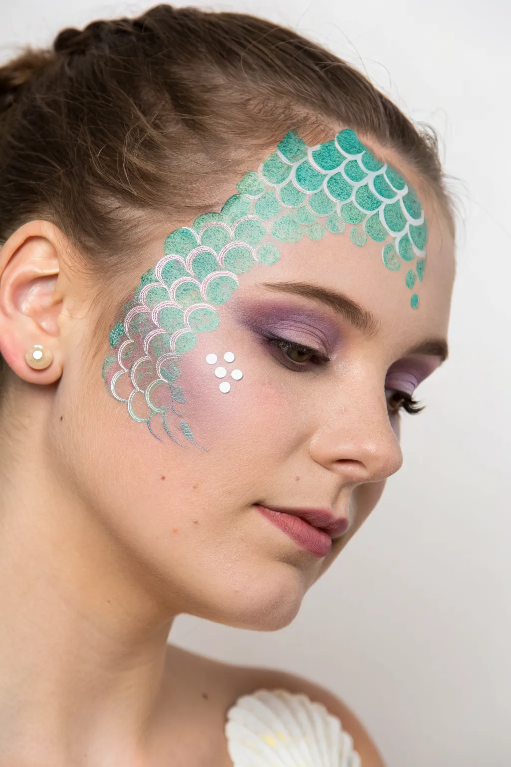 Mermaid scales half-face paint with pearly sea shimmer, minimalist ocean glow and clean contrast