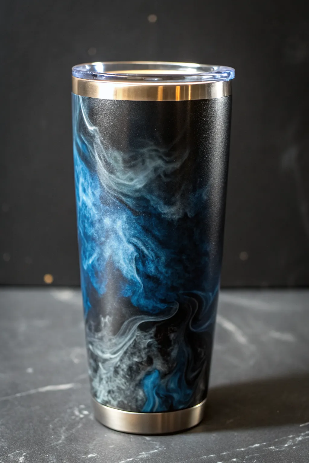Steel-blue smoke swirls on a glossy black epoxy tumbler, minimal and bold with depth