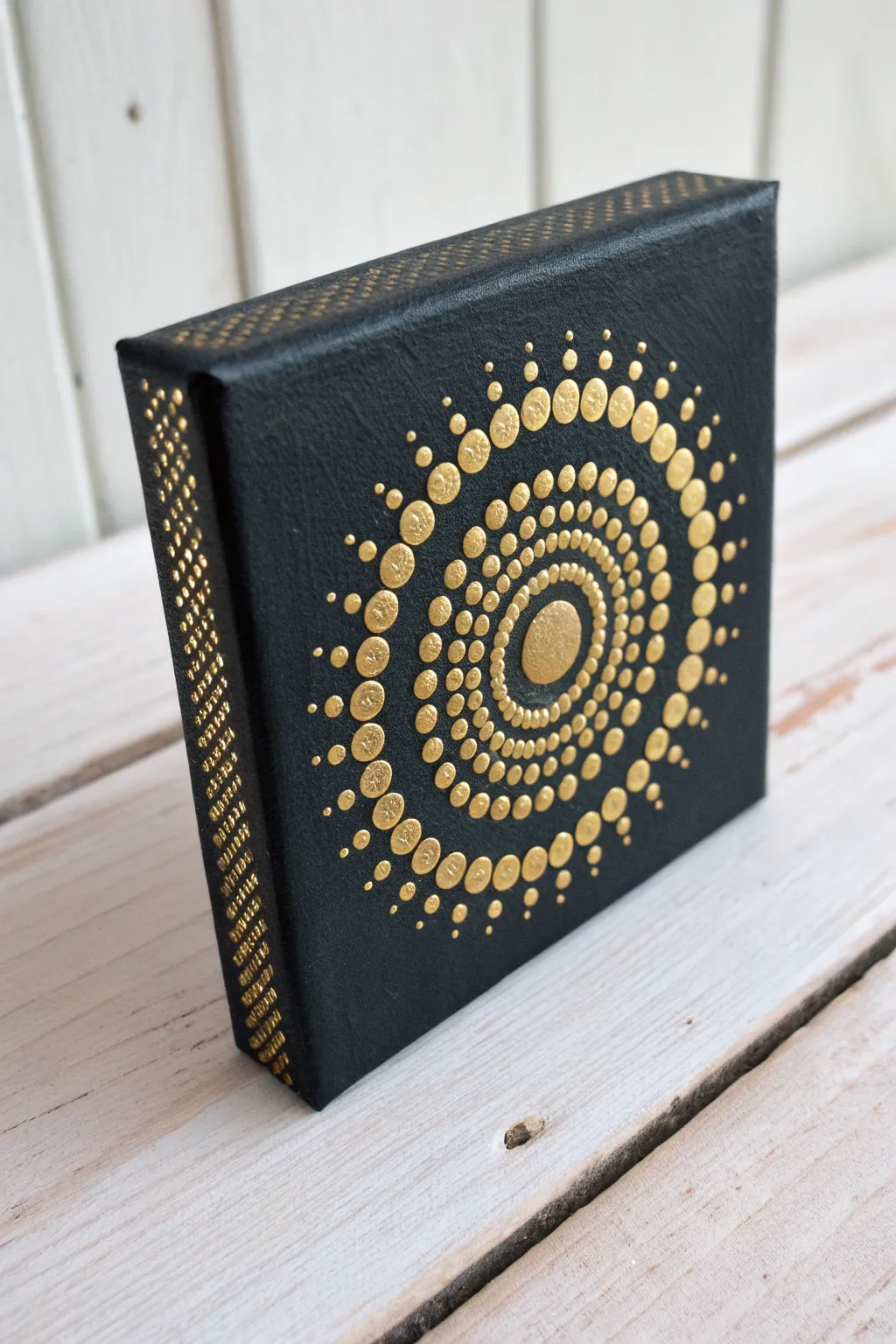 Gold mandala dot ring on mini black canvas, simple and striking with a soft boho glow