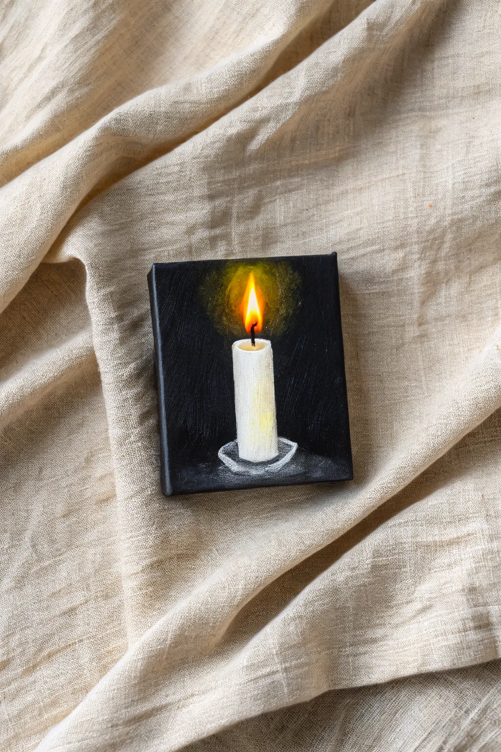 Capture the cozy glow of a solitary candle with this high-contrast mini painting idea.