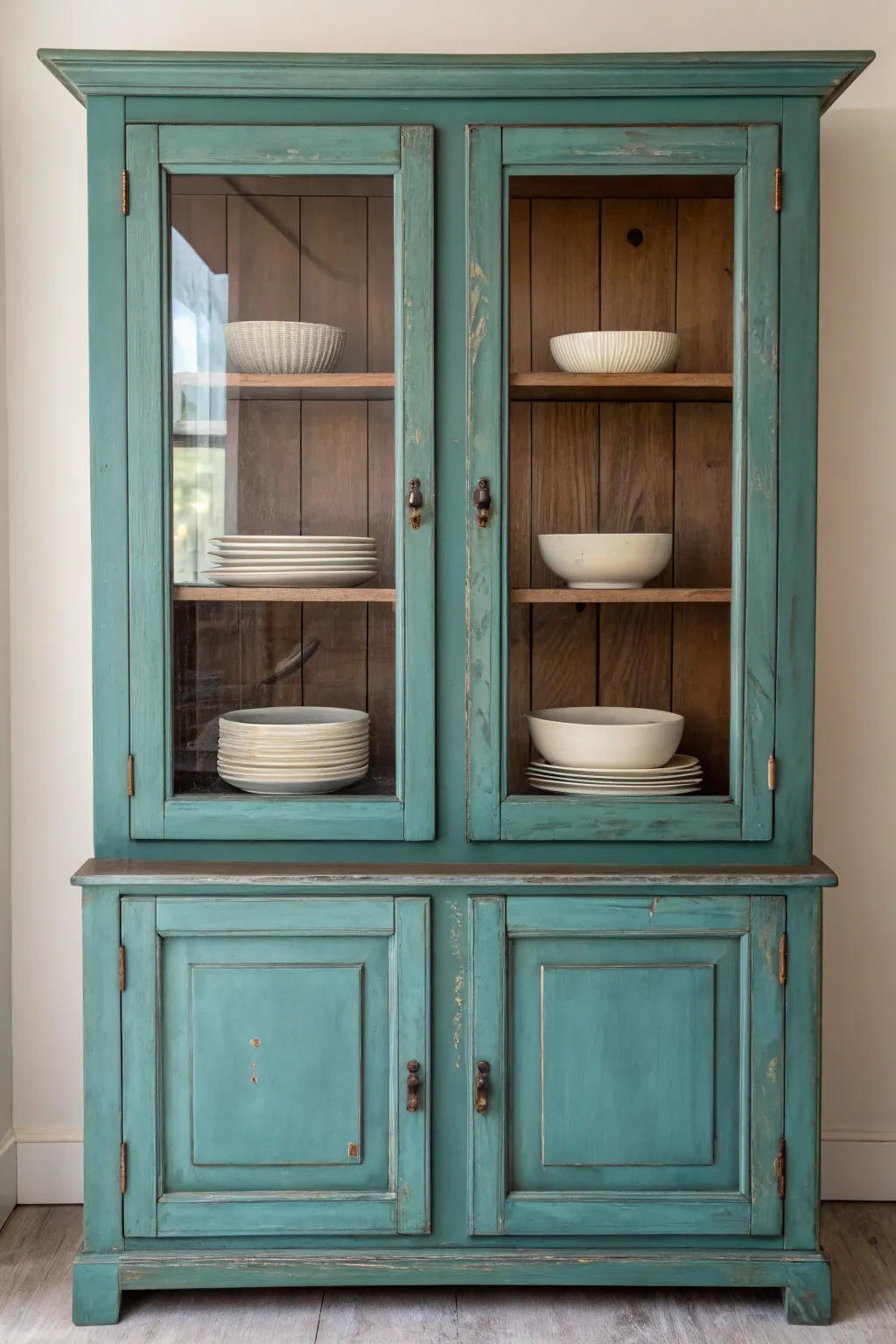 Richly painted glass-door hutch styled with pale ceramics for crisp, modern contrast.