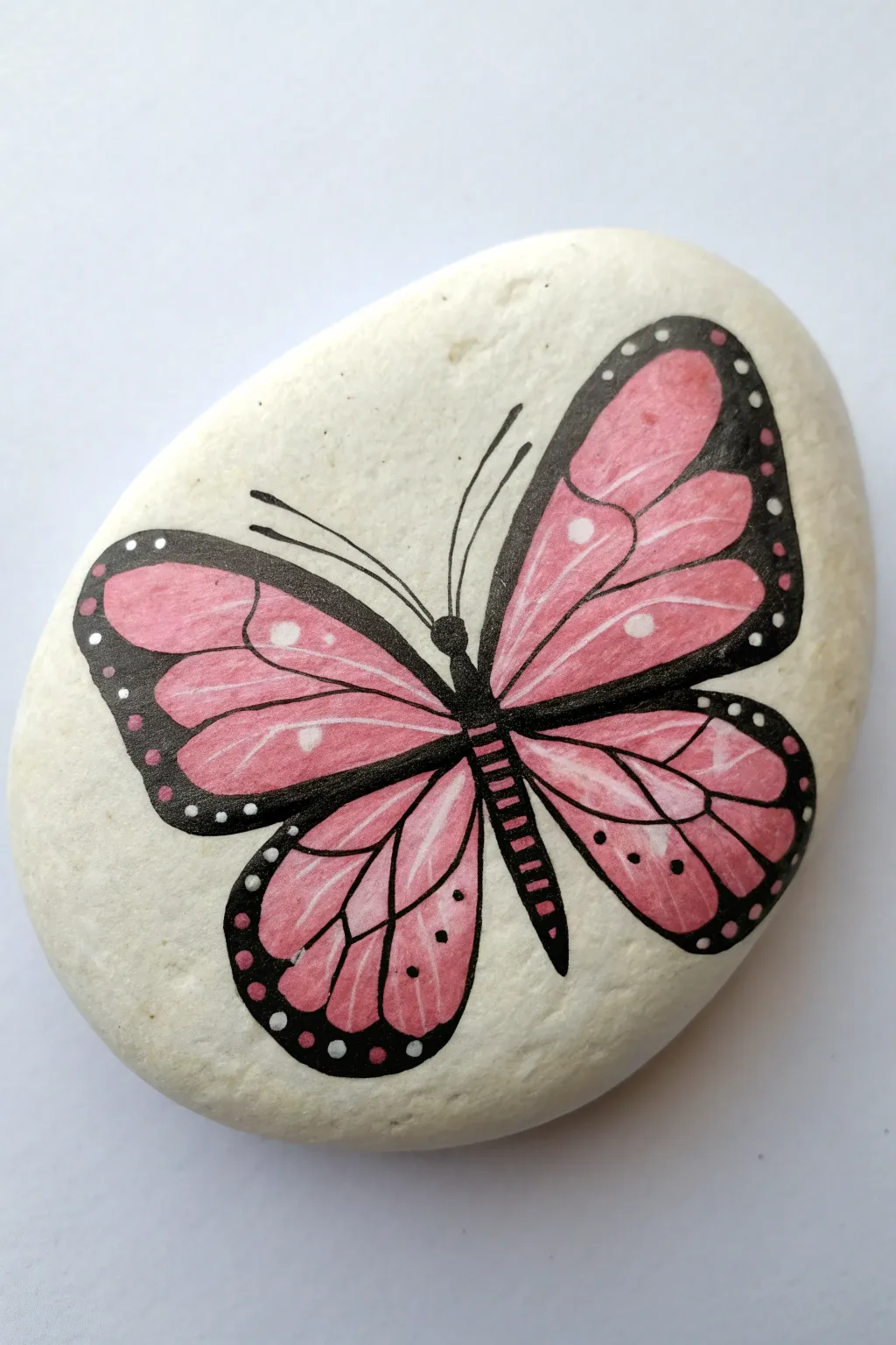 Pink butterfly rock: layered dots and stripes for a sweet, minimalist boho paint idea.
