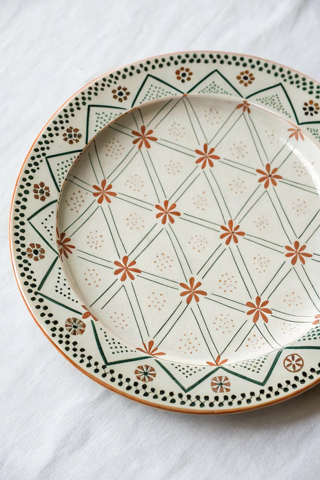 Tile-inspired geometry on a hand-painted plate, minimal palette, perfect symmetry, bold contrast.