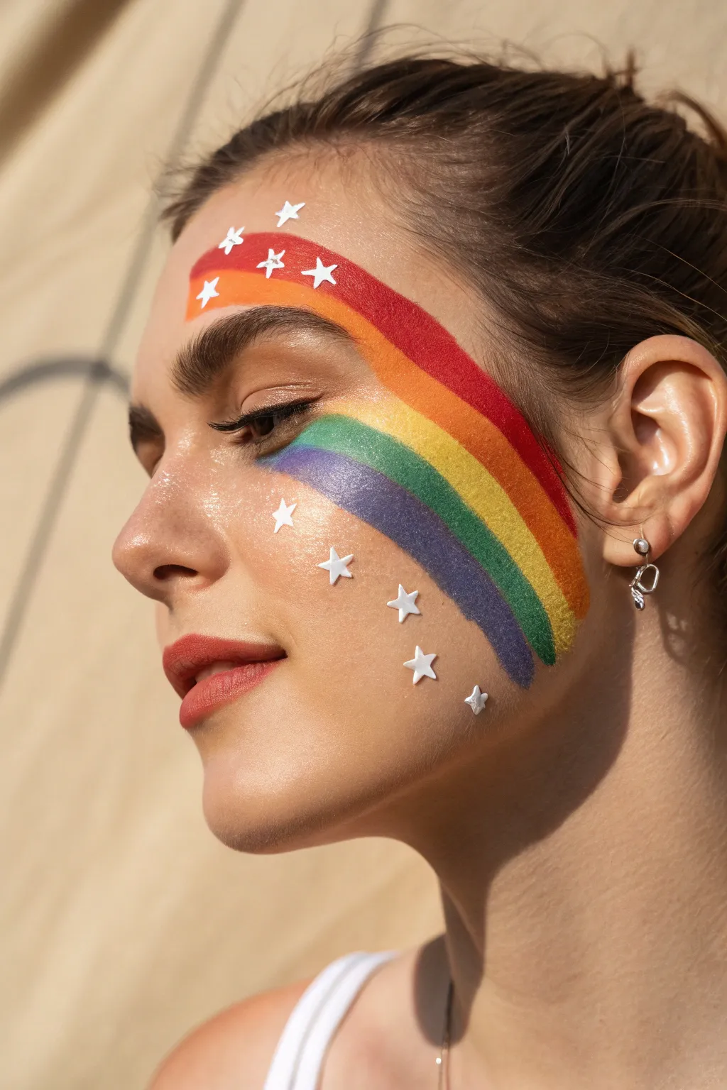 Bold rainbow bands with delicate white starburst highlights for a chic minimalist face paint look