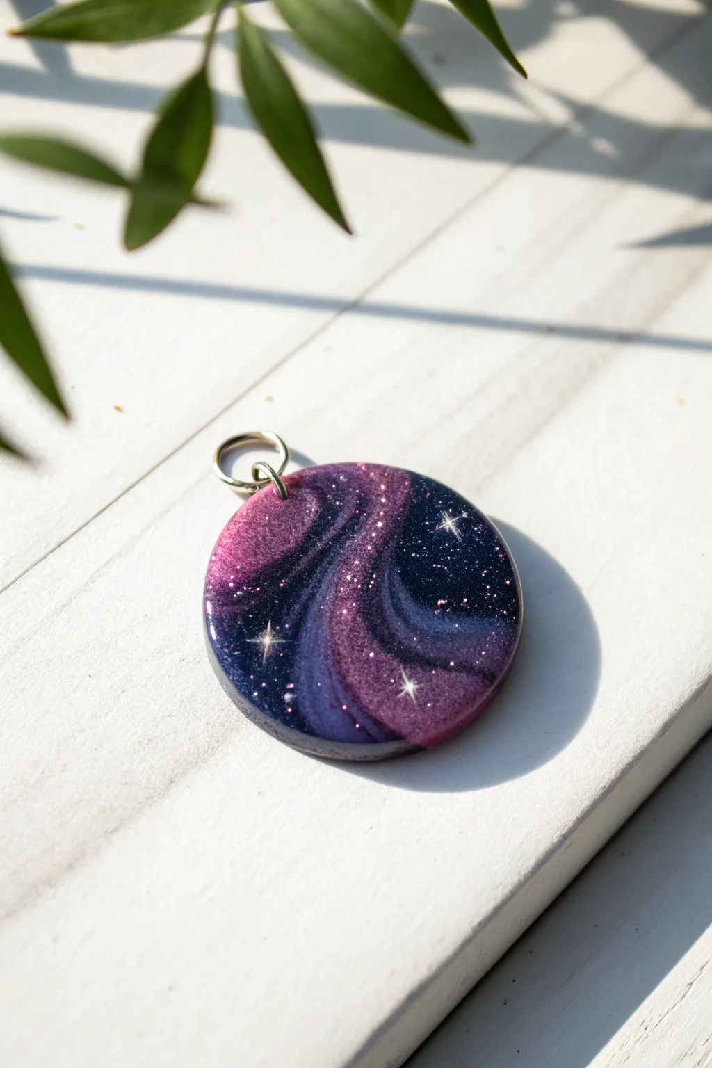 DIY galaxy resin charm: deep navy and purple swirls with starry glitter on clean white.