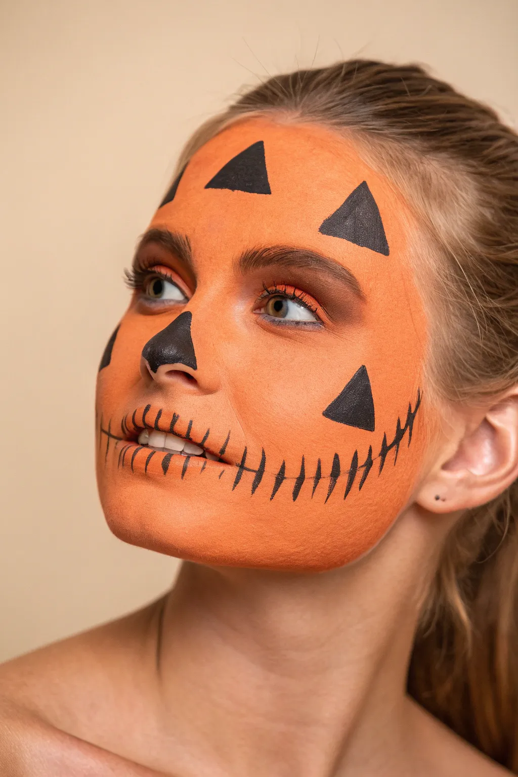 Easy scary pumpkin face paint with triangle eyes, jagged grin, and simple rib lines