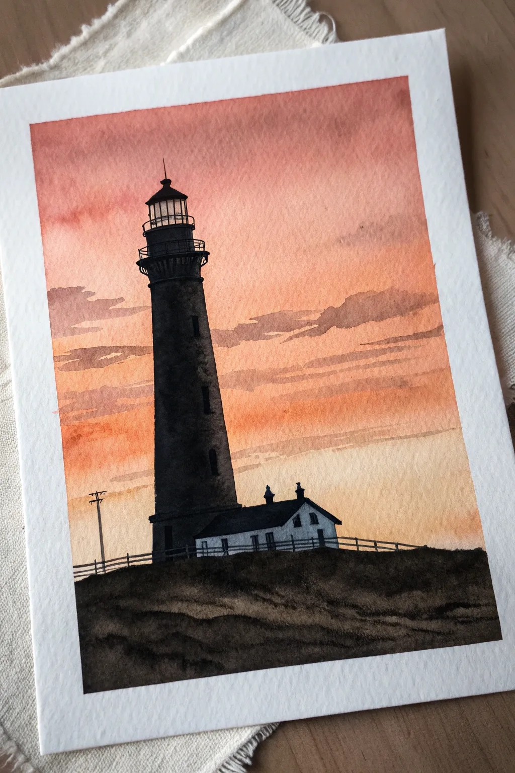 Paint a bold lighthouse silhouette with a soft beam slicing through a glowing sunset wash.