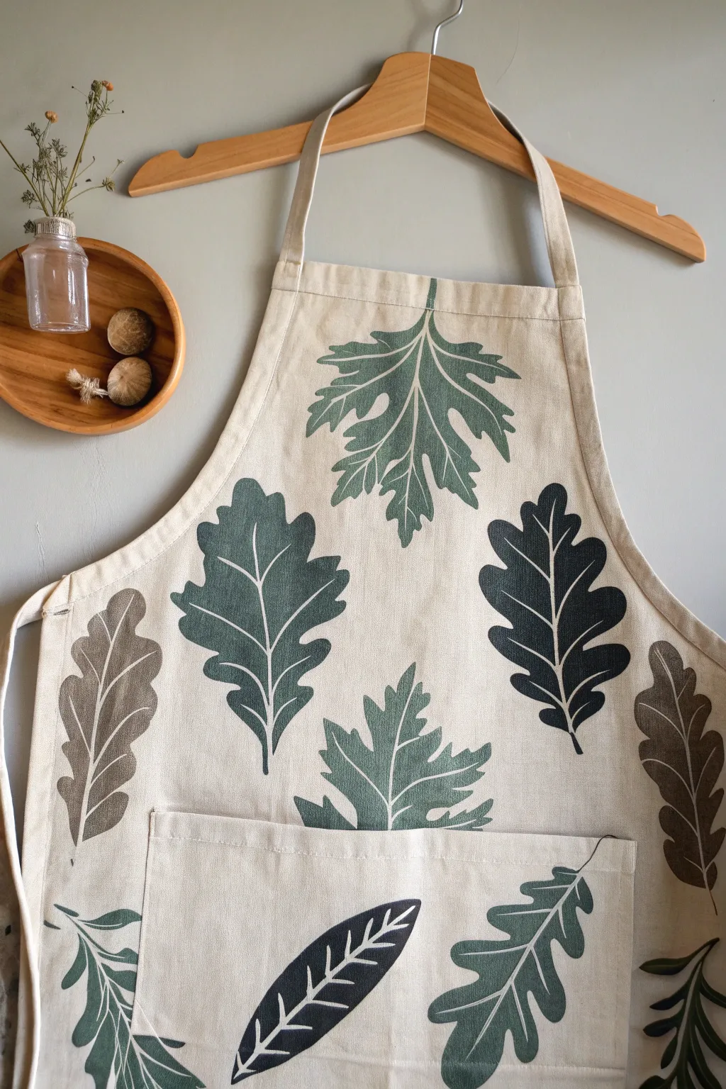 Scandi-minimal apron art: bold negative space leaves in sage, terracotta, and charcoal tones