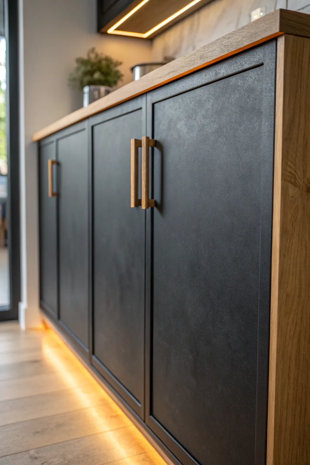 Matte black cupboard front with warm wood handle and cozy light for modern boho contrast