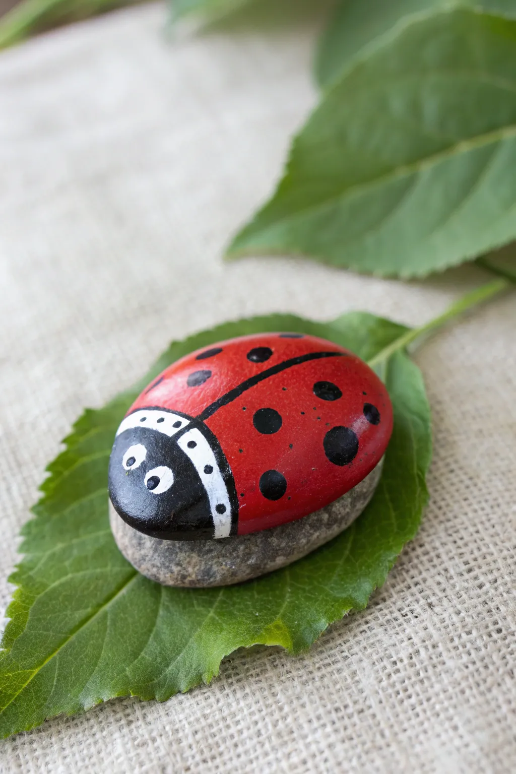 Ladybug polka-dot rock on a green leaf, bold red and black for a cute mini masterpiece