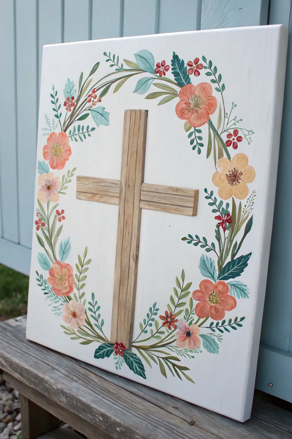 Minimal Easter canvas: wooden cross with a soft wildflower wreath on a pale sky wash