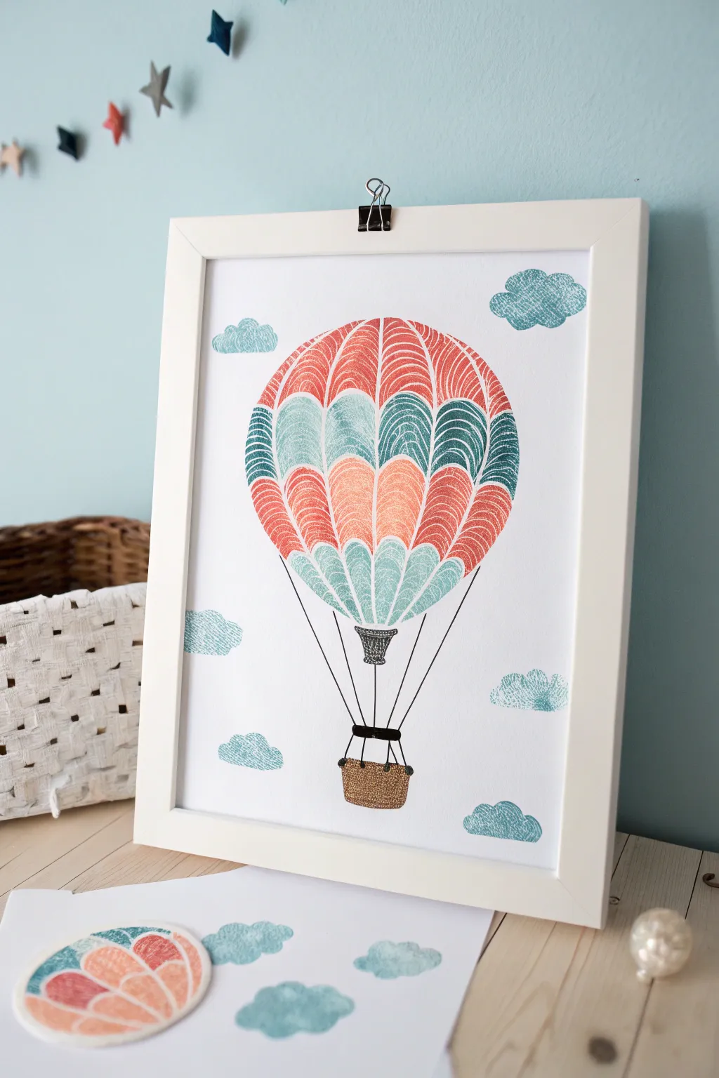 Make a fingerprint hot air balloon: bold oval prints, airy sky, sweet tiny basket.