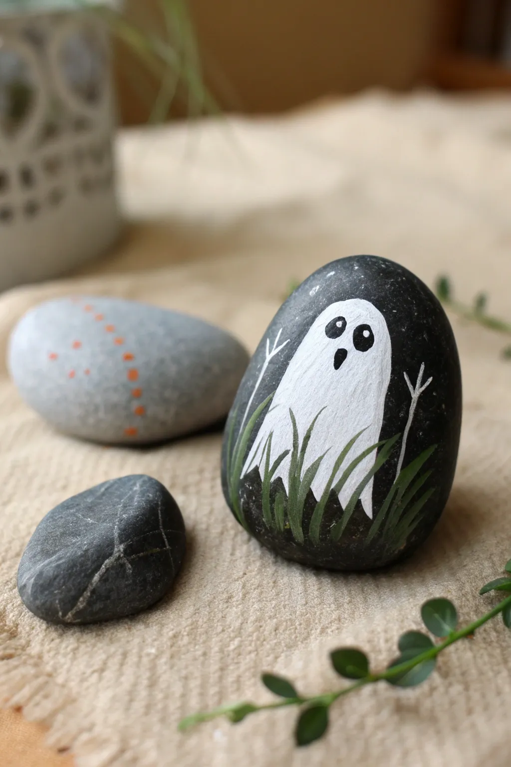 Peekaboo ghost rock painting with bold tombstone contrast, cozy minimalist Halloween charm.