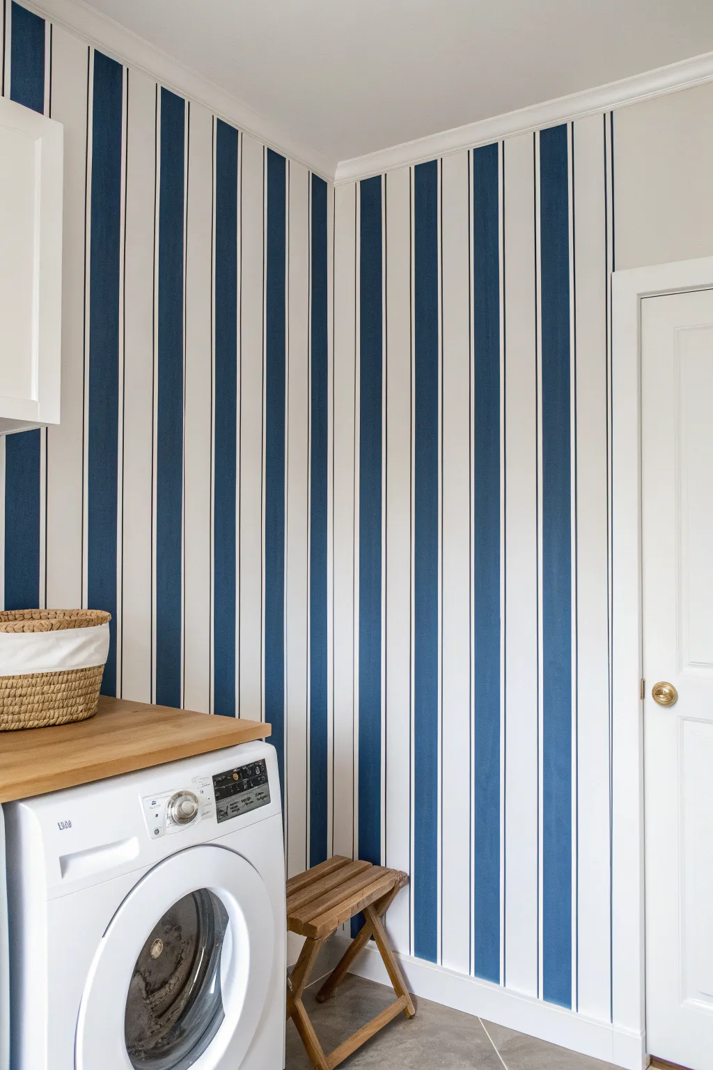 Navy and warm-white painted stripes create instant graphic style in a calm, minimal laundry nook.
