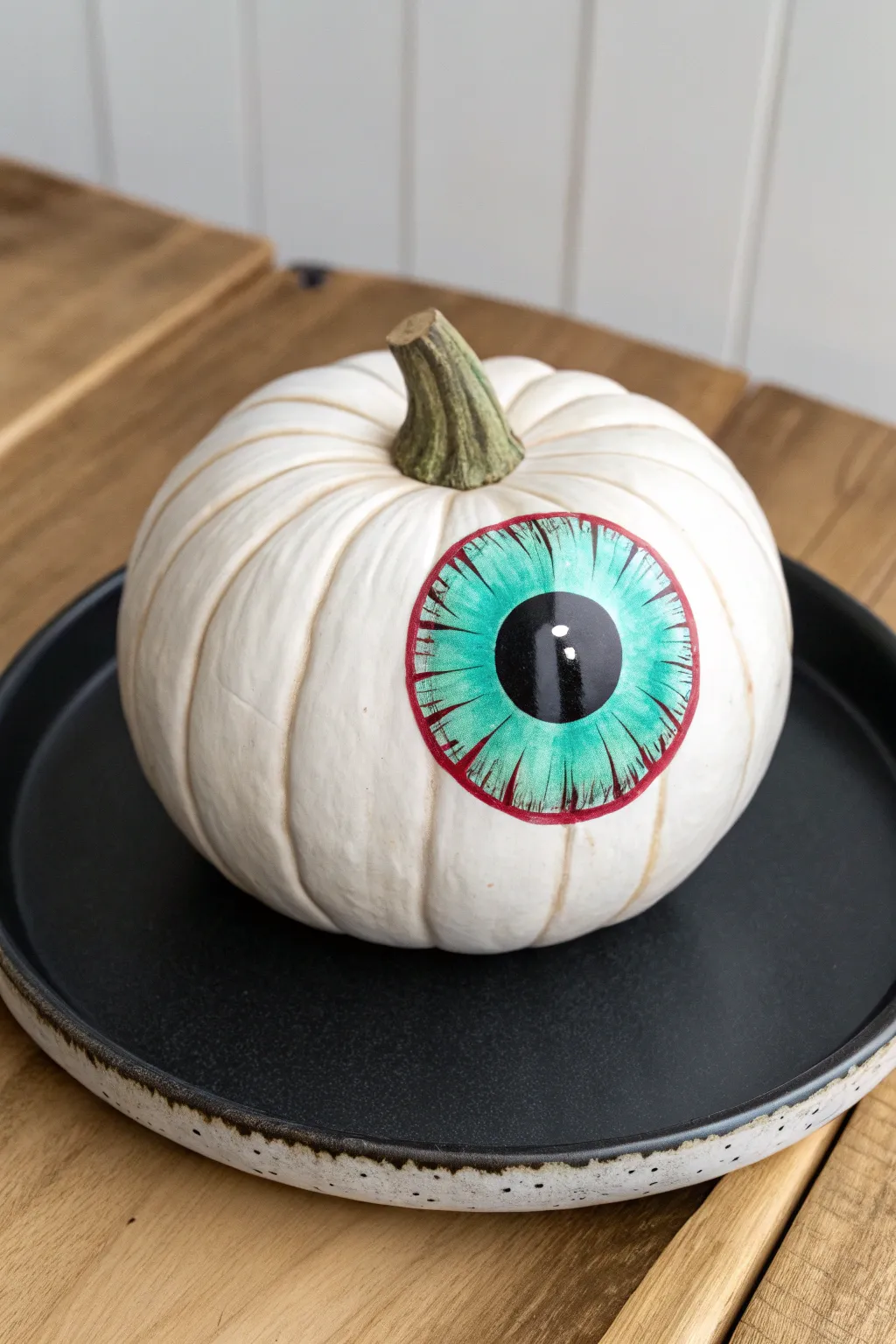 Spooky chic white pumpkin eyeball with bold iris shine, minimalist Halloween centerpiece contrast