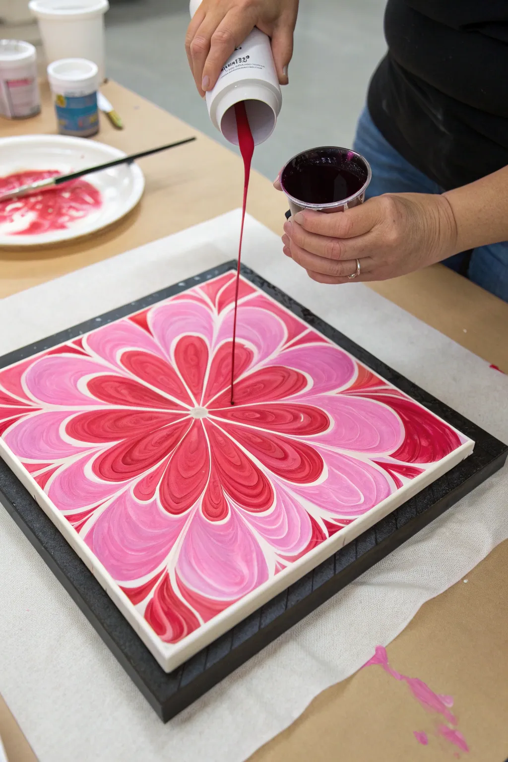 Pink-to-red bloom pour with a bold dark border, captured mid-pour for crisp contrast