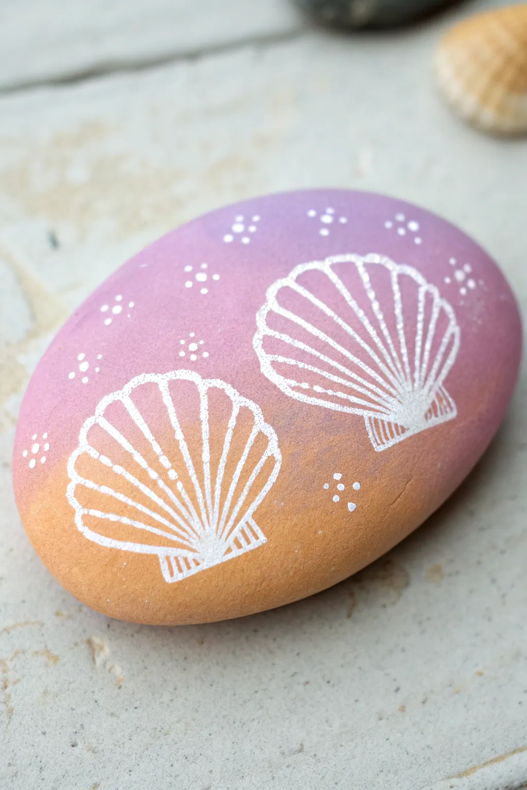 Pastel ombre seashell rock with crisp outlines and dotted glow for chic preppy beach vibes.