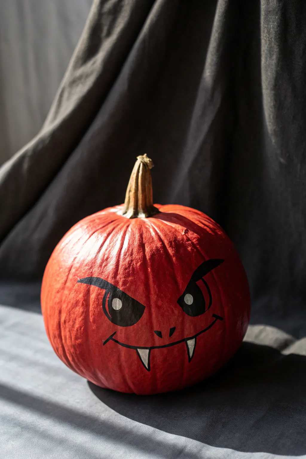 Minimal red pumpkin vampire face with dramatic shadows for a chic, spooky Scandinavian vibe