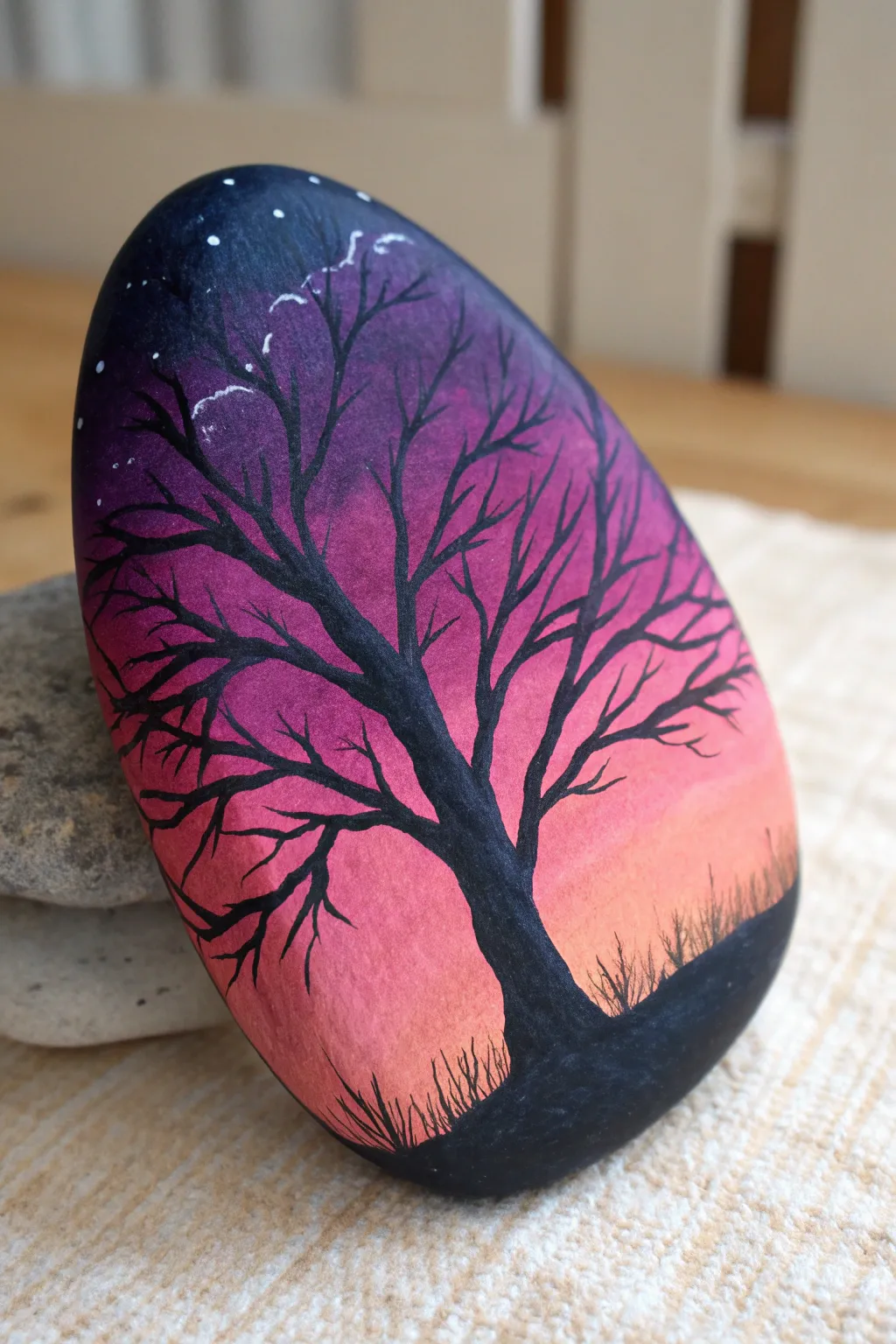 Moody sunset rock painting in magenta and navy with bare branch silhouette, minimalist boho.