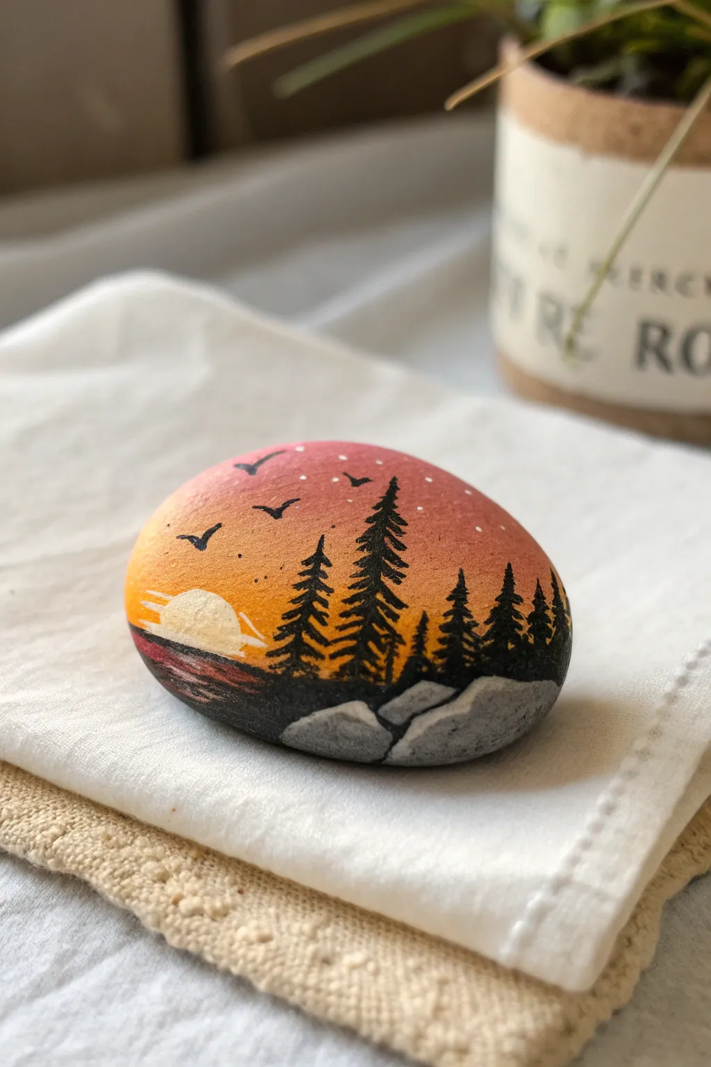 Tiny sunset landscape on a smooth stone, minimalist and warm with bold contrast