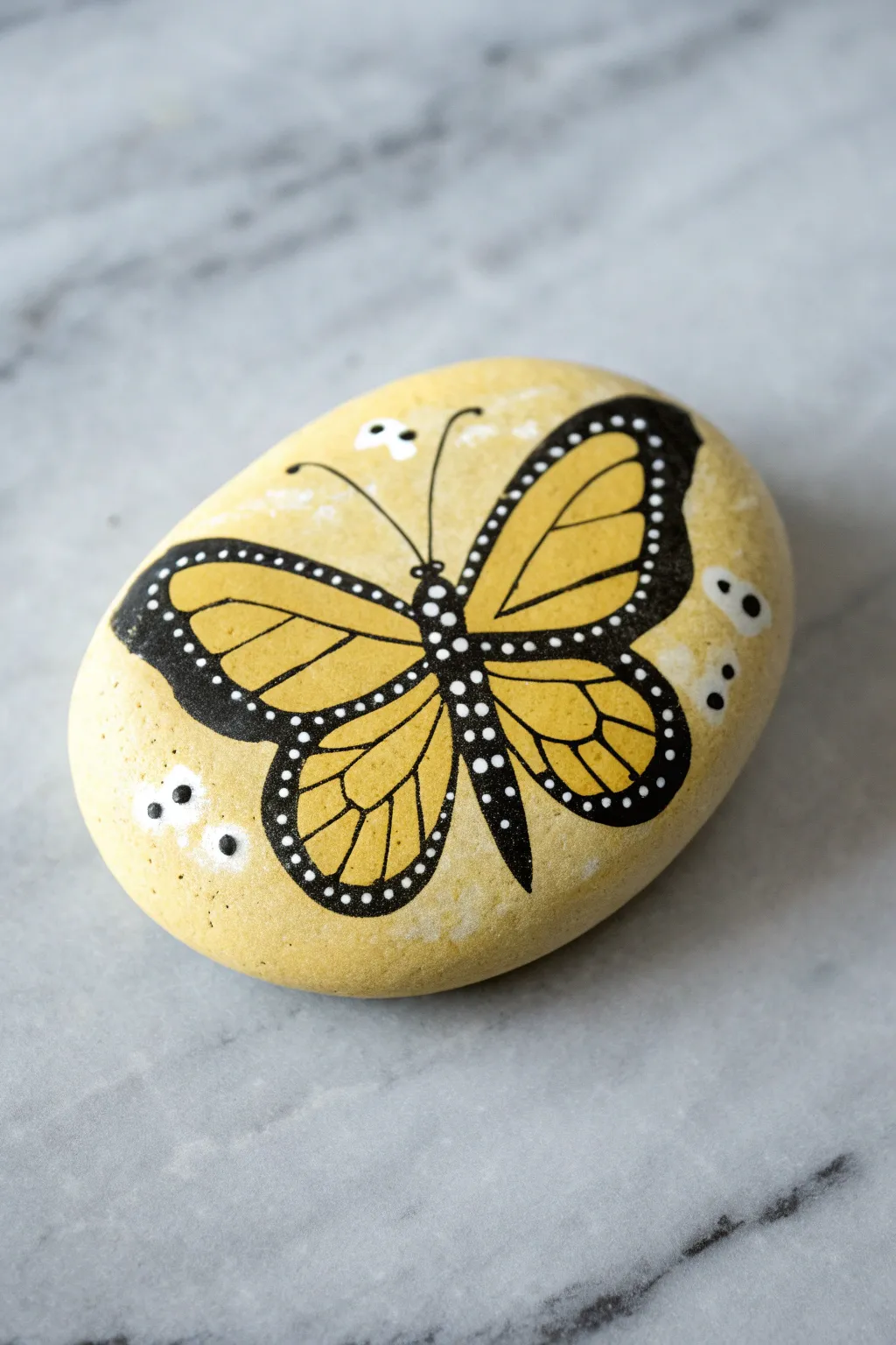 Yellow butterfly wings on a smooth rock, bold black outlines and simple white dots for easy charm