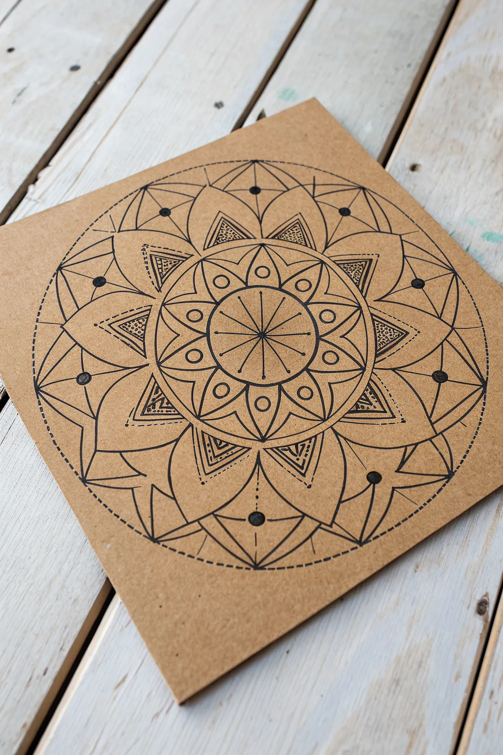 Geometric mandala on cardboard with bold contrast, clean symmetry, and subtle pencil compass marks
