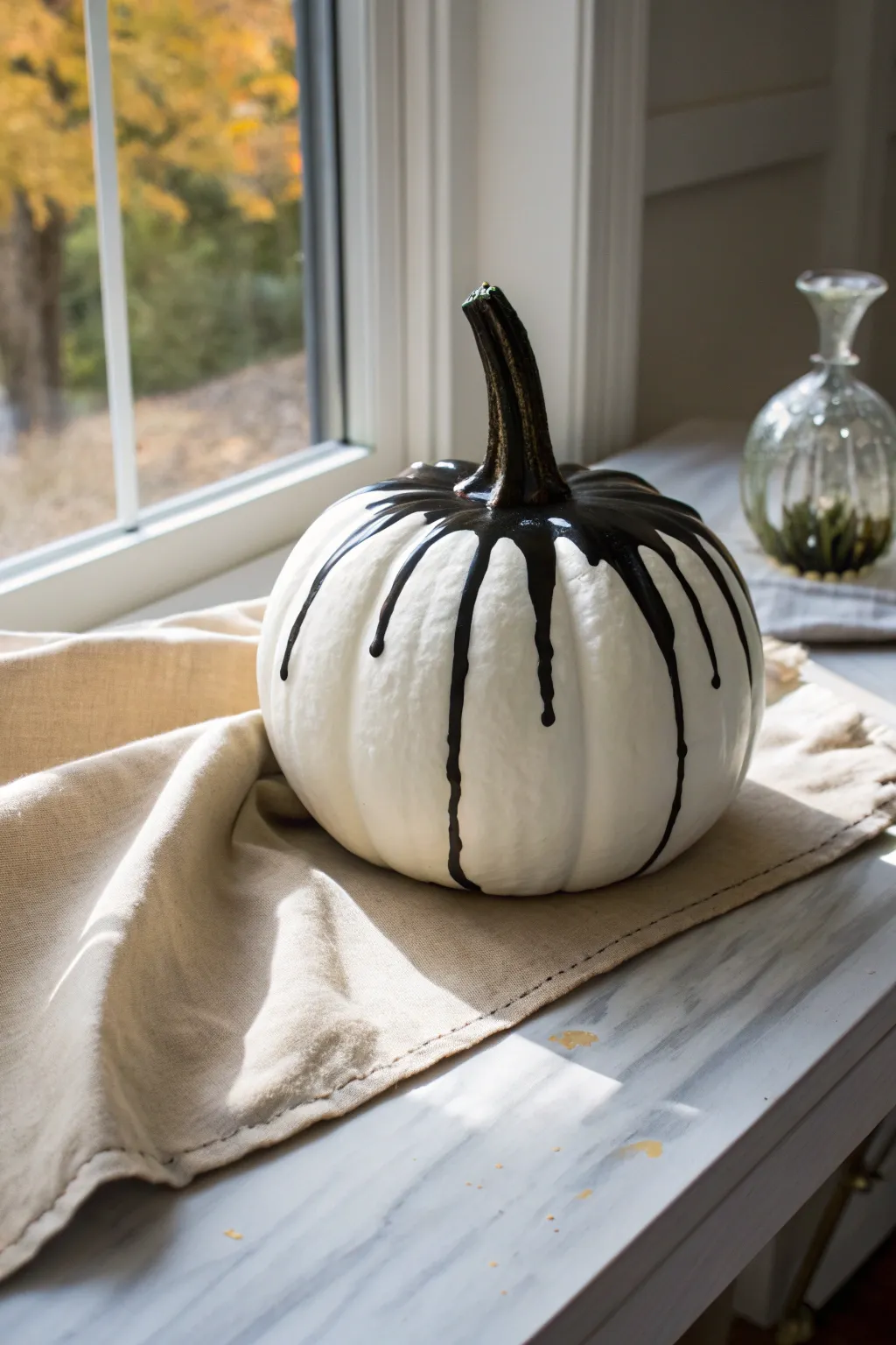Cool white pumpkin with glossy black paint-pour drips for a bold, modern Halloween edge