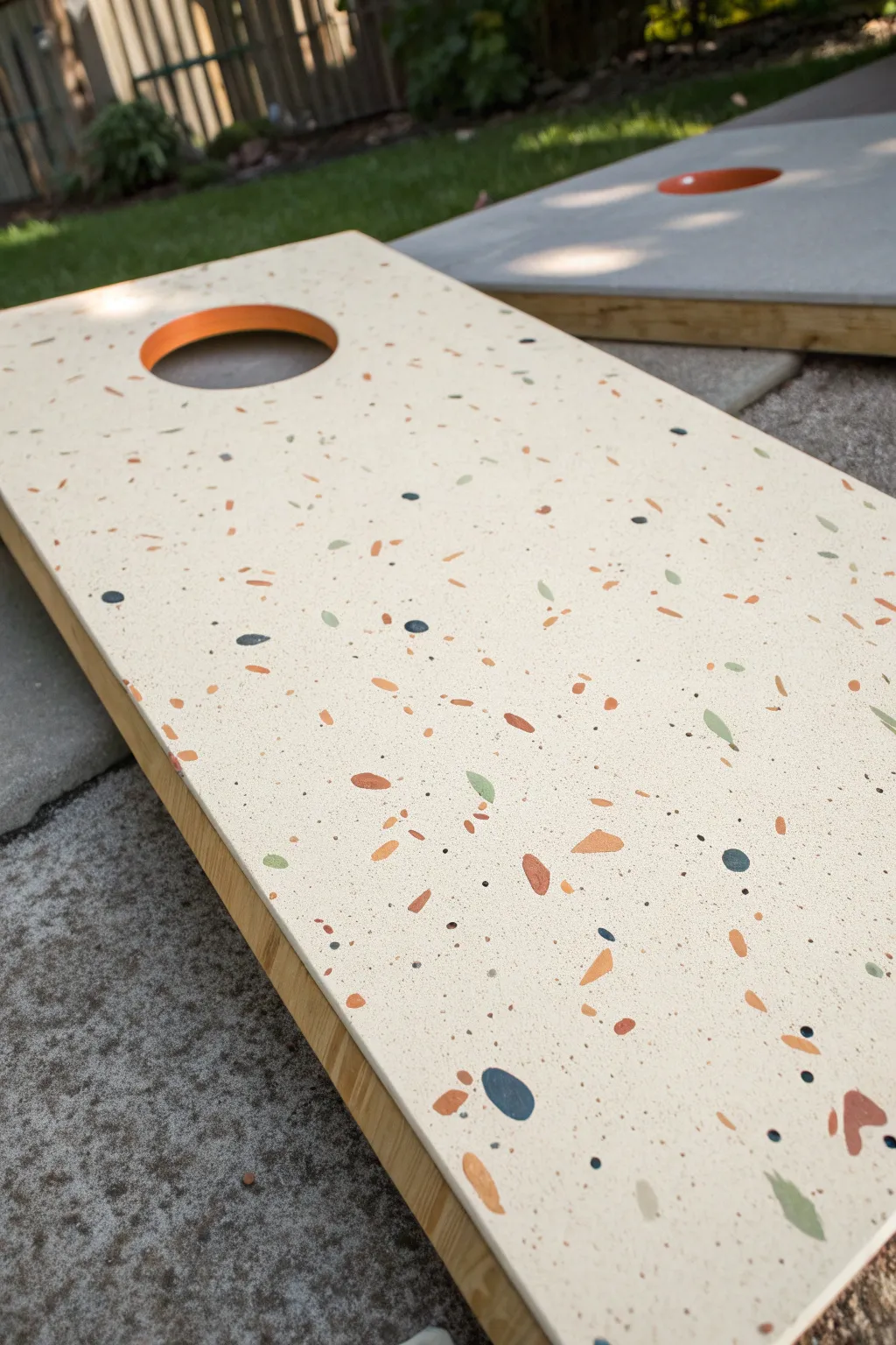 Speckled confetti halo around the cornhole hole, minimalist base, smooth sealed finish.
