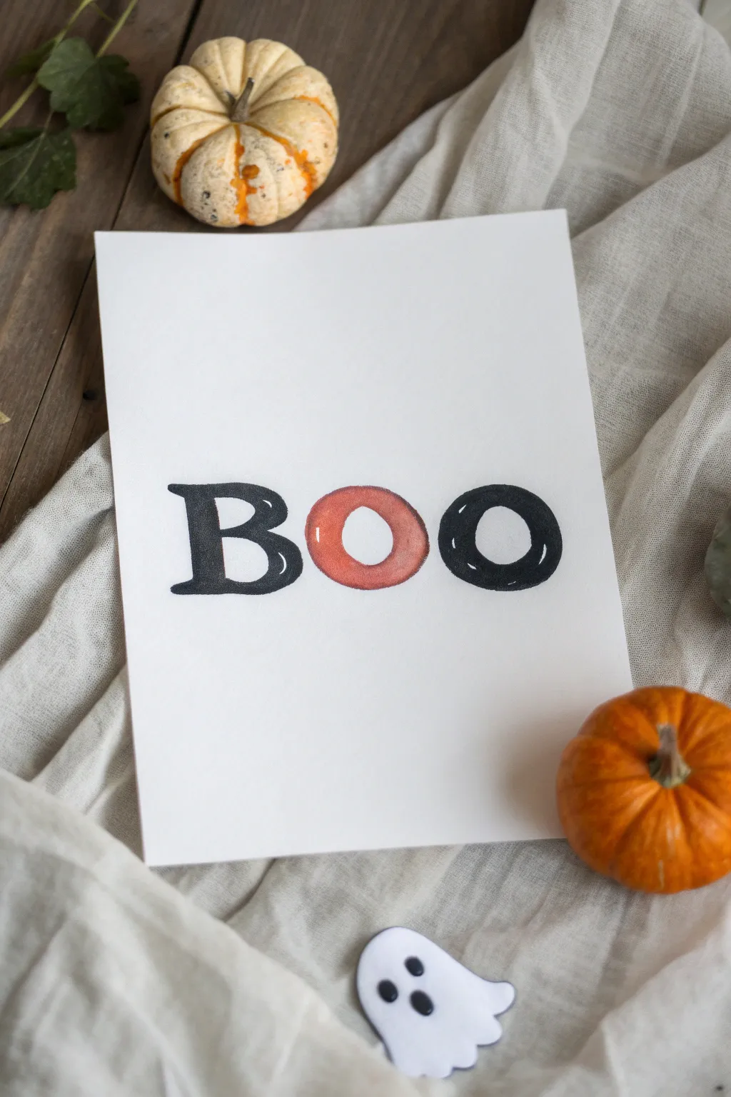 Easy Halloween painting: bold BOO with a pumpkin O and ghost O in minimalist black and orange