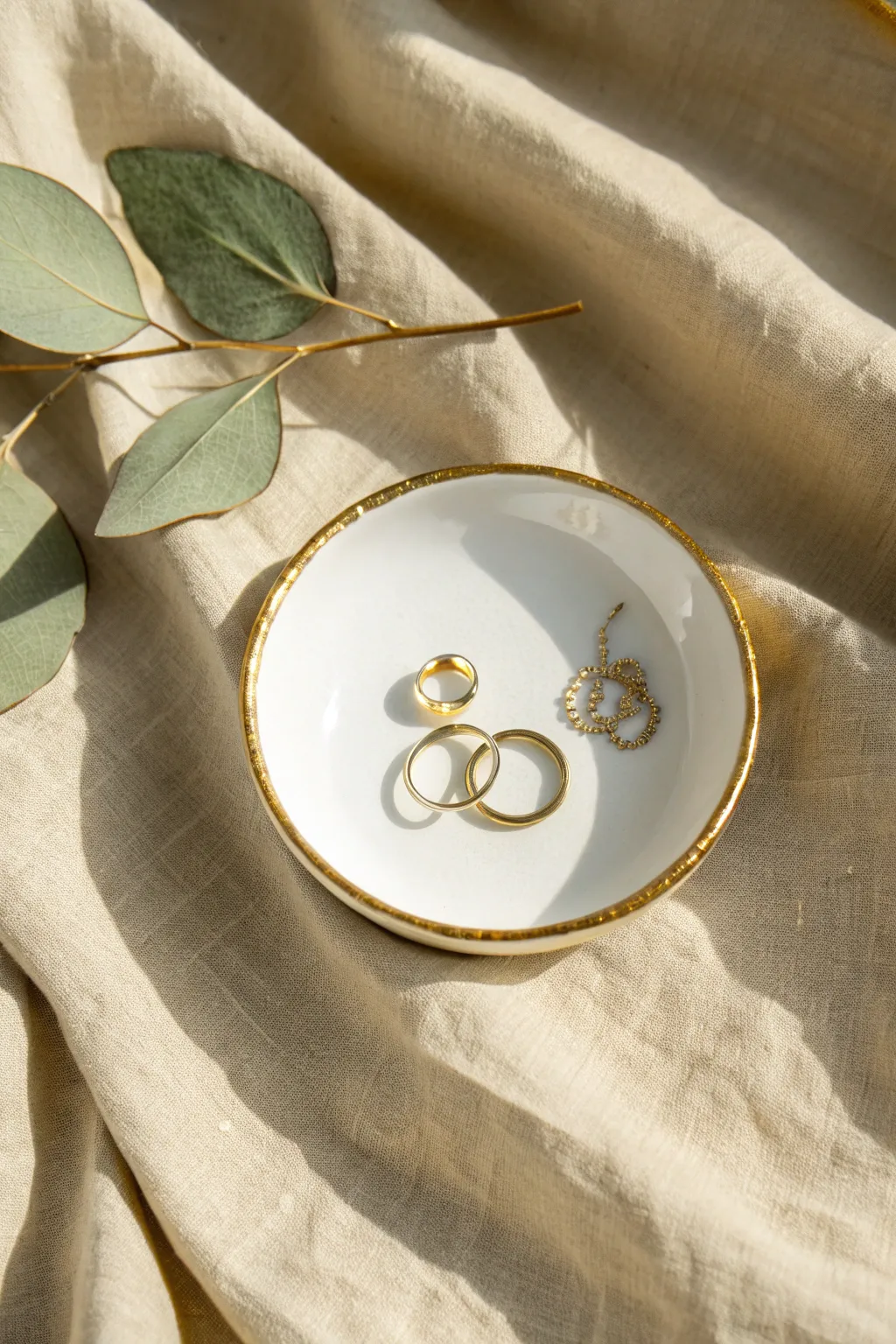 Glossy white jewelry dish with a metallic gold rim and minimal leaf detail, luxe yet simple