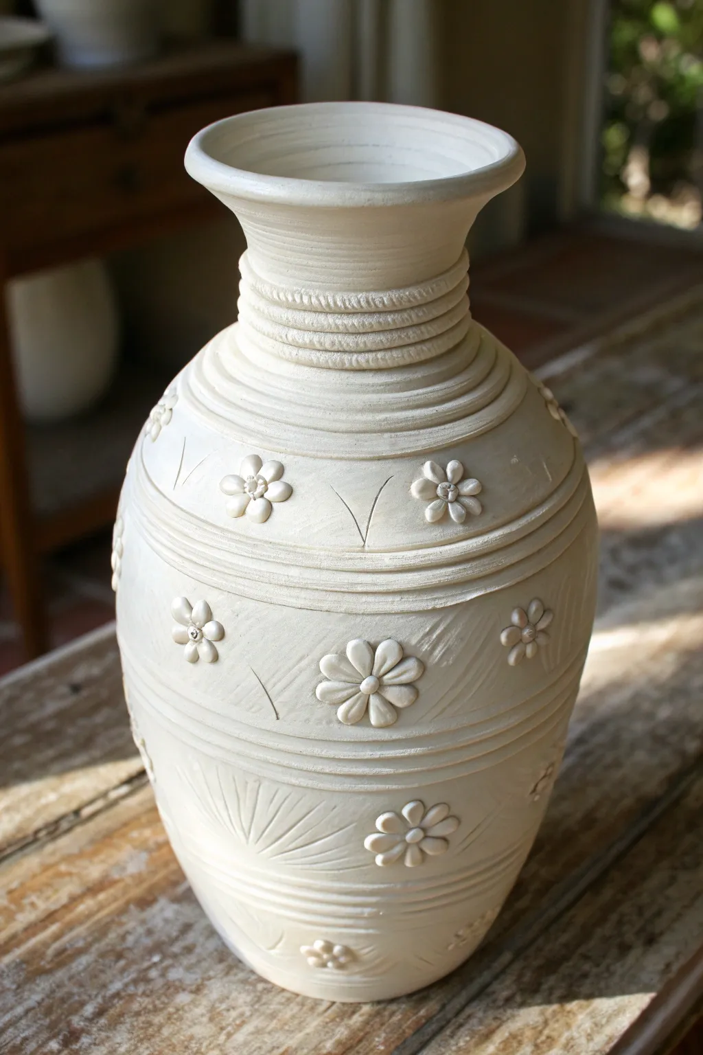 Raised coil lines and tiny floral appliqués bring sculptural 3D texture to a calm white vase.