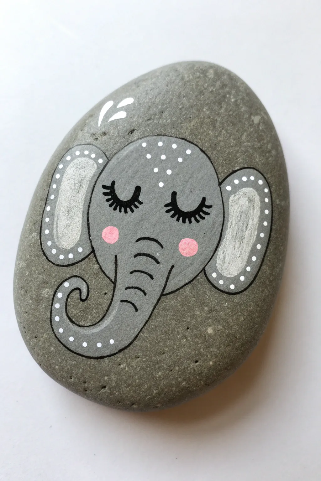 Sweet elephant rock painting with a curved trunk, soft lashes, and minimalist boho styling
