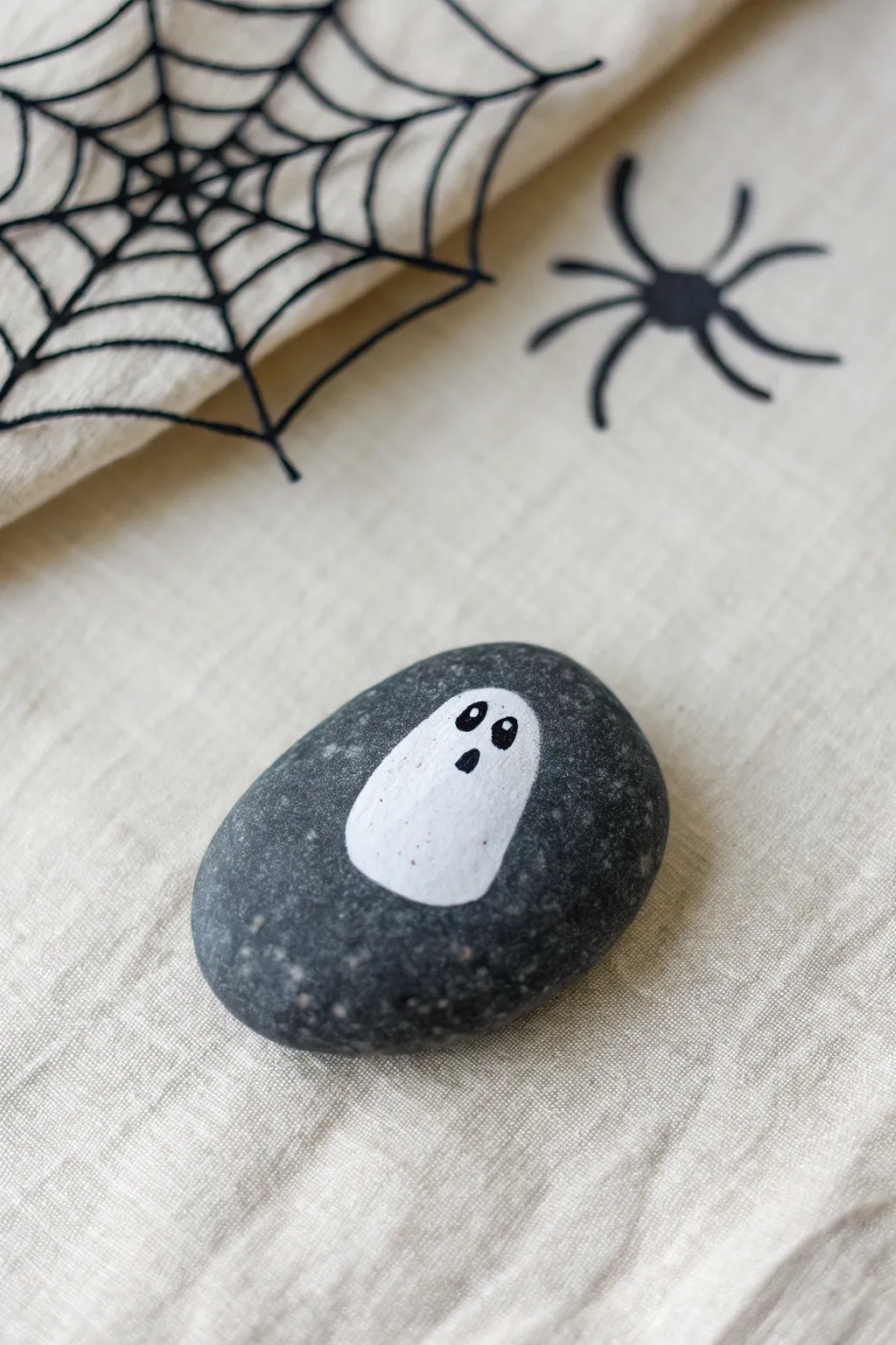 Simple ghost rock with a delicate spiderweb corner, bold contrast, and cozy minimalist vibes.