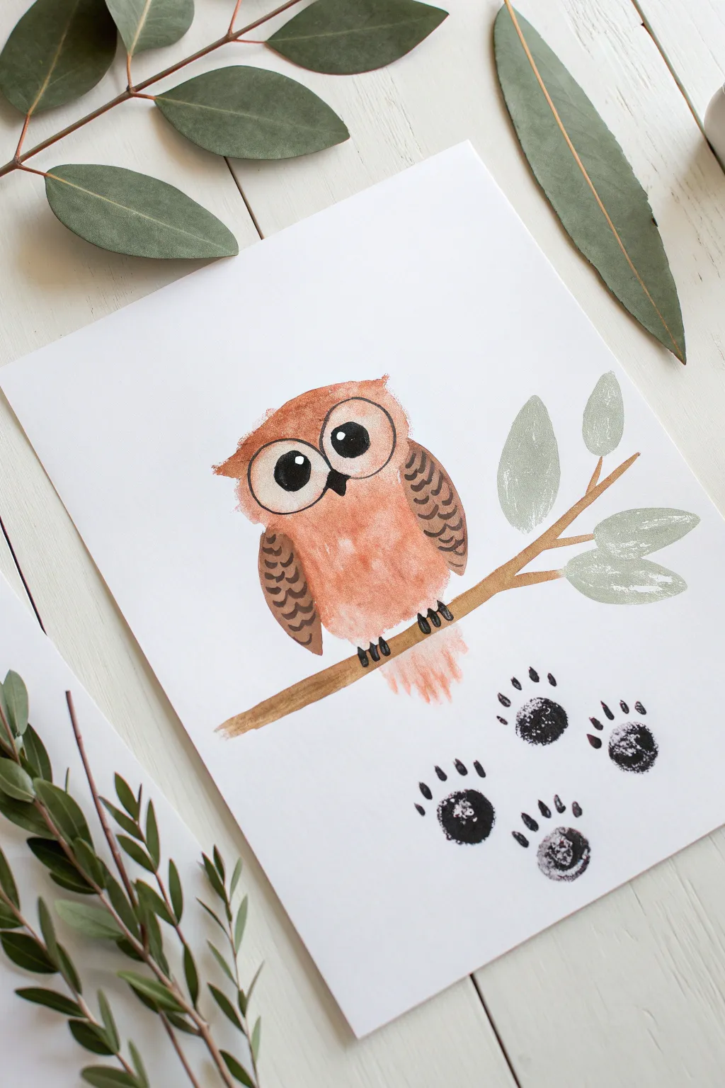 Minimal handprint owl on a branch with leafy fingerprints, cozy woodland toddler painting idea